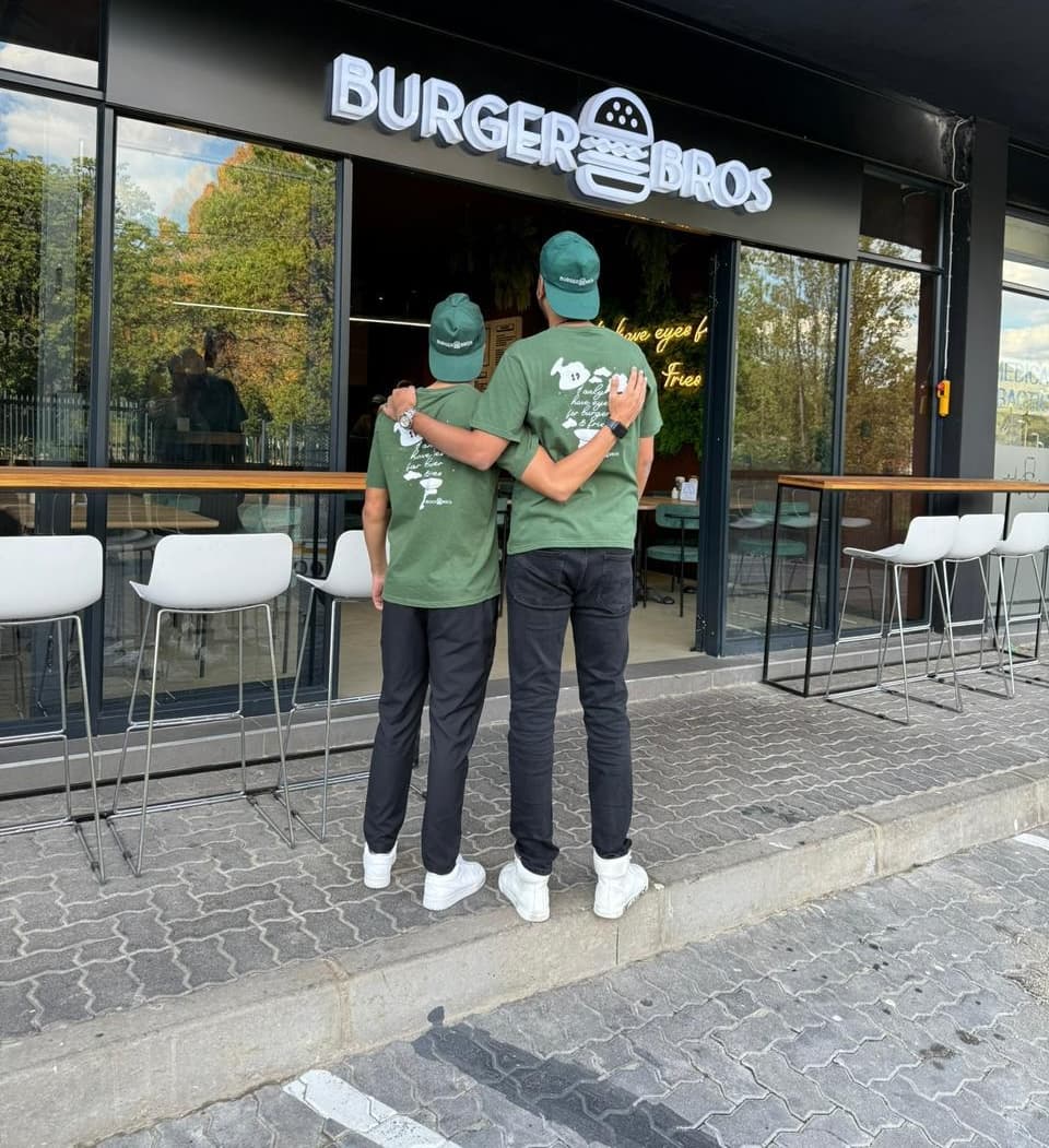 The two Burger Bros founders in their green tees outside the storefront