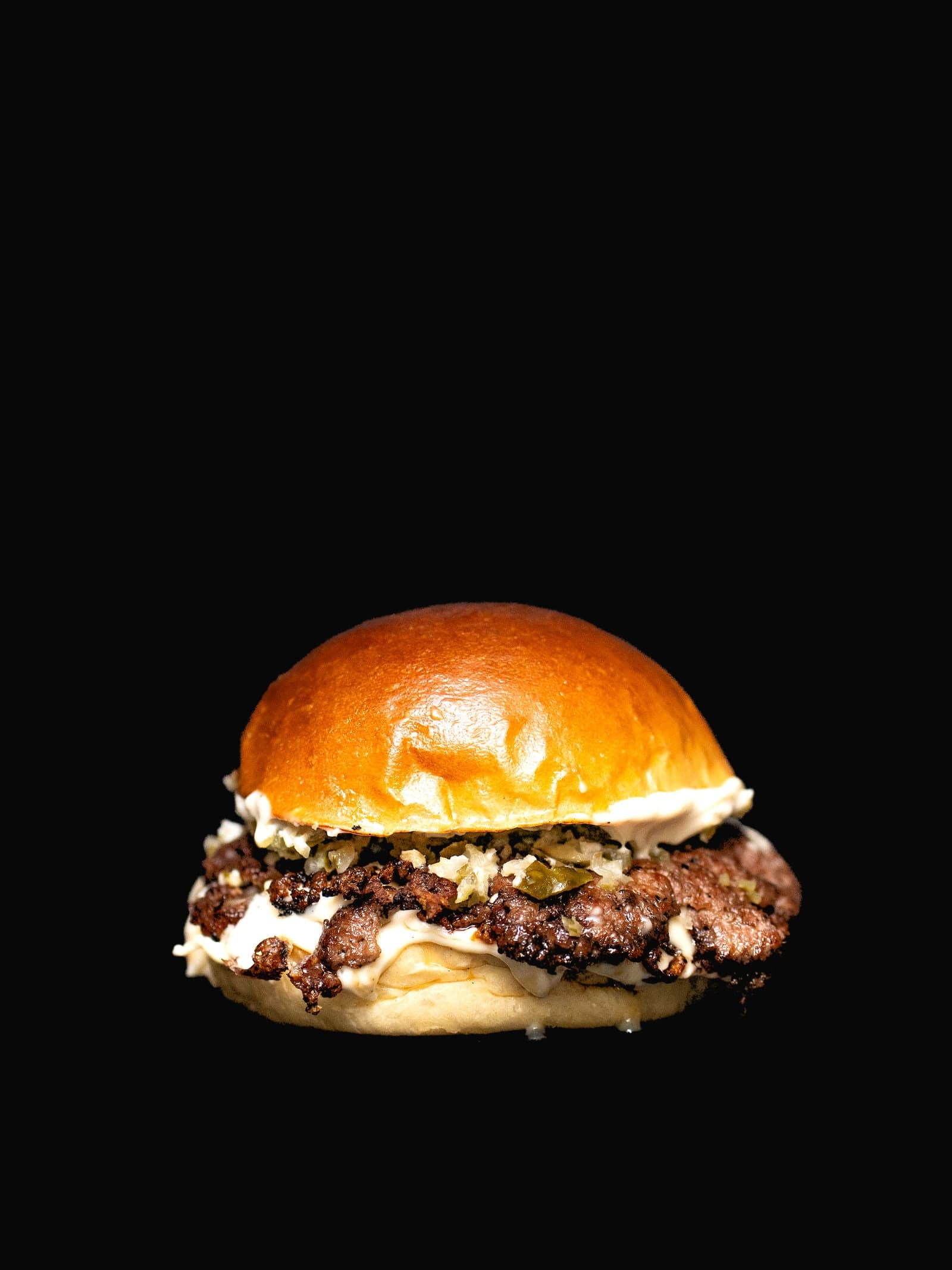 Truffle Smash — Smashed patty under a wave of truffle mayo and melted cheese, finished with crisp pickles on golden brioche.